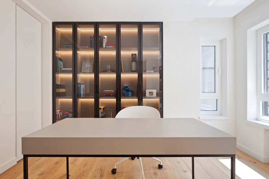 “Despacho moderno minimalista con escritorio contemporáneo, estantería iluminada y decoración elegante en tonos neutros.