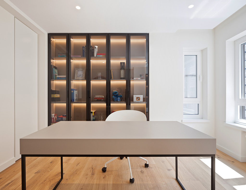 “Despacho moderno minimalista con escritorio contemporáneo, estantería iluminada y decoración elegante en tonos neutros.