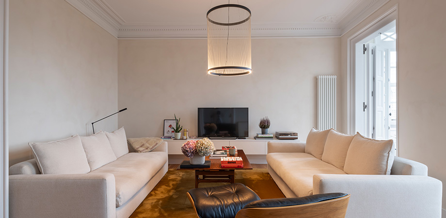 Salón moderno y elegante con sofás blancos, mesa de centro, iluminación cálida y decoración minimalista contemporánea