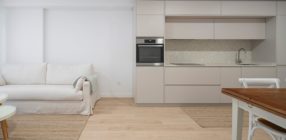 Salón y cocina minimalista de concepto abierto con muebles beige, decoración nórdica y acabados en madera clara.