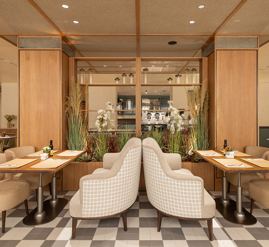 Dos mesas de comedor flanqueadas por sofás curvos enfrentados en un espacio decorado.