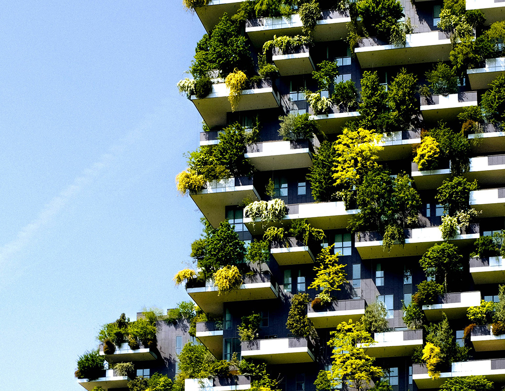 Edificio vertical ajardinado con abundante vegetación integrada, ejemplo de arquitectura sostenible y renaturalización urbana.