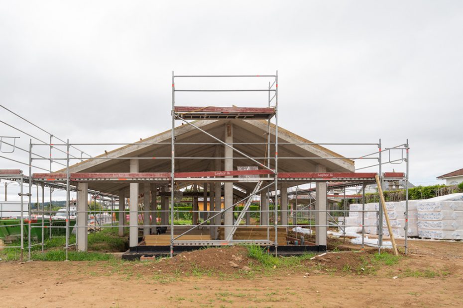 El exterior de una estructura de hormigón en construcción, rodeada de andamios y materiales.
