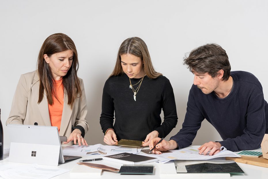 Personal de Malasa revisando planos y muestras de materiales sobre una mesa, trabajando en el desarrollo de un proyecto.
