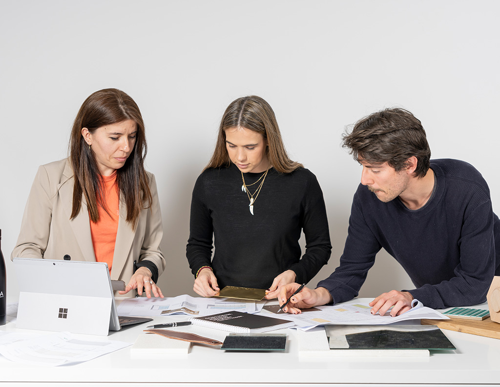 Personal de Malasa revisando planos y muestras de materiales sobre una mesa, trabajando en el desarrollo de un proyecto.