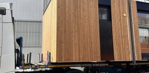 Módulo prefabricado con acabado en madera siendo transportado para su instalación en obra.