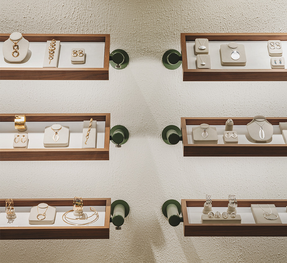 Estantes de madera anclados a la pared blanca mostrando colecciones organizadas de collares y pulseras.