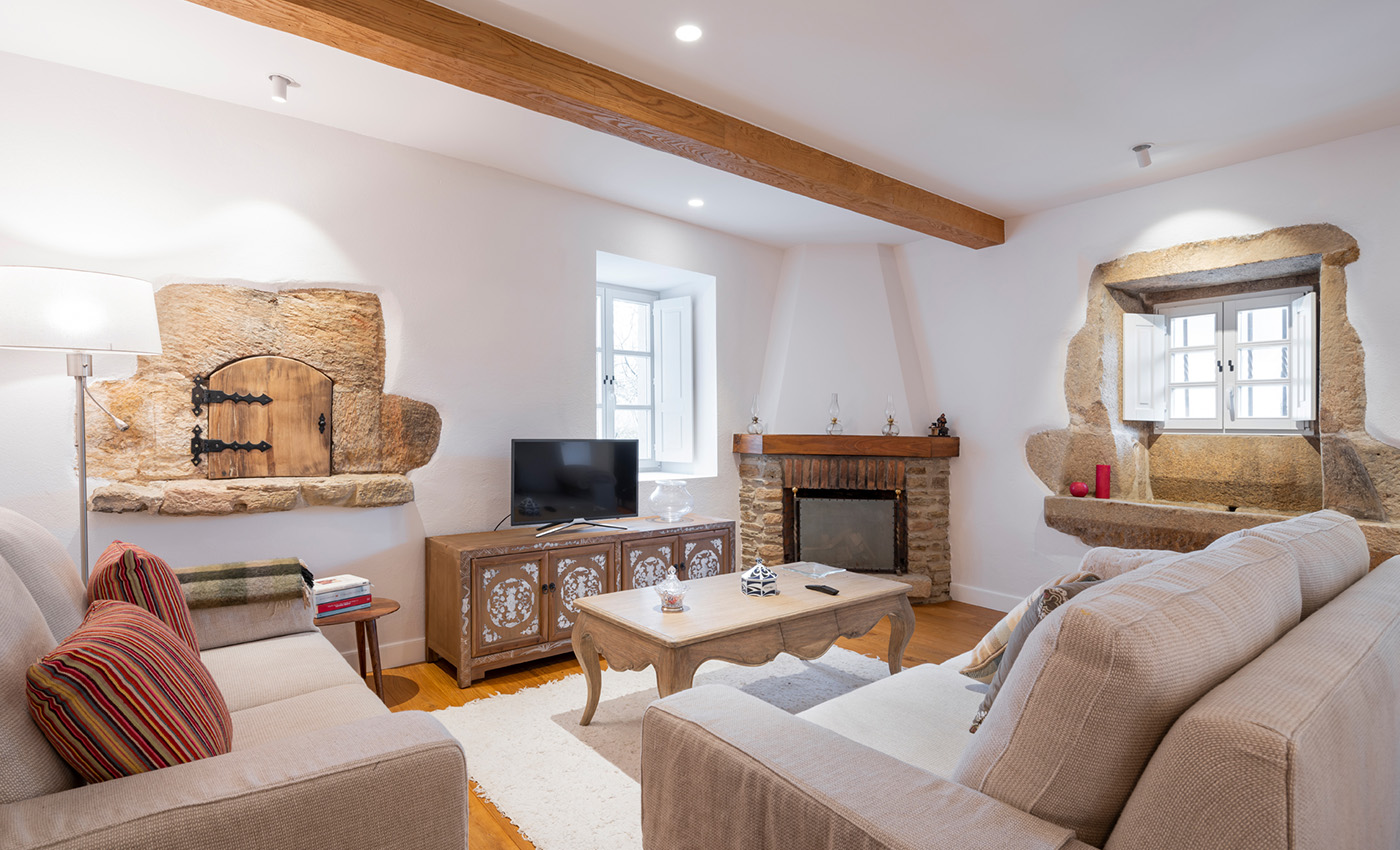 Espacioso y acogedor salón comedor con vigas de madera, chimenea de piedra, alfombra oriental y lámpara de mimbre.