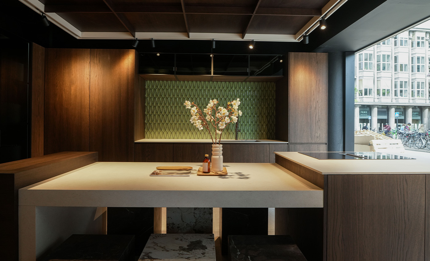 Cocina moderna de lujo con gabinetes de madera oscura, isla central e impresionante salpicadero verde.