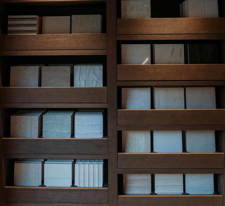 Estantería de madera oscura ordenada con muestras y texturas variadas de azulejos y cerámica.