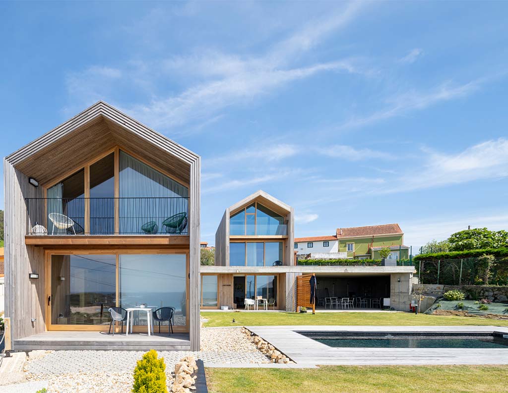 Vivienda modular terminada de diseño moderno con fachadas de madera, grandes ventanales, terraza, jardín exterior y una piscina.