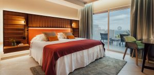 Dormitorio de hotel moderno con gran cabecero de madera a juego con el mobiliario.