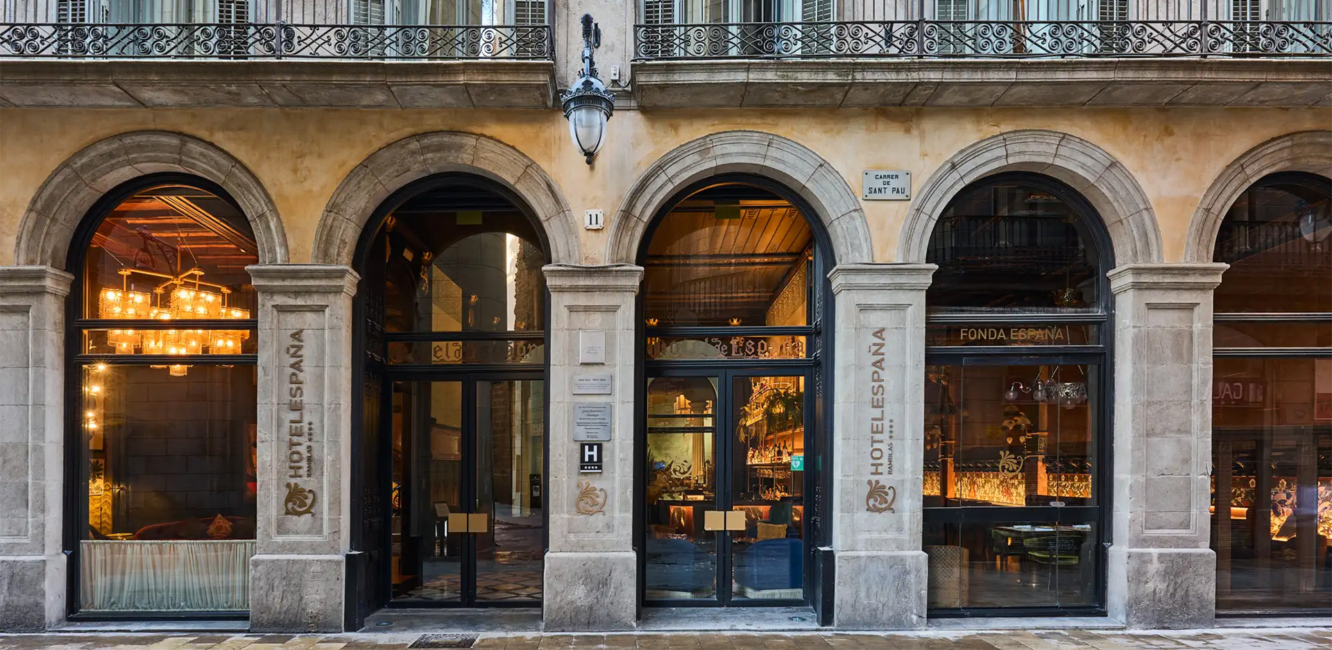 Fachada clásica de un edificio con grandes arcos de piedra y escaparates de cristal.