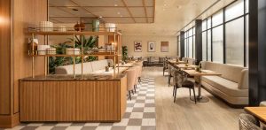 Comedor de restaurante con mesas de madera, suelo ajedrezado e iluminación cálida y natural.