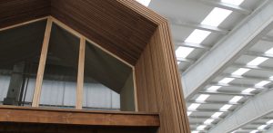 Estructura de un módulo volumétrico con cubierta a dos aguas y revestimiento de madera en un proceso industrial