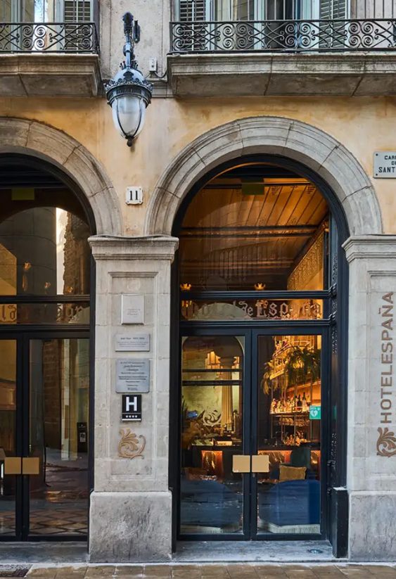 Fachada clásica de un edificio con grandes arcos de piedra y escaparates de cristal.