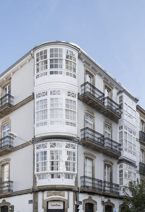 Esquina de edificio histórico con fachadas blancas y balcones acristalados múltiples en Plaza Lugo.