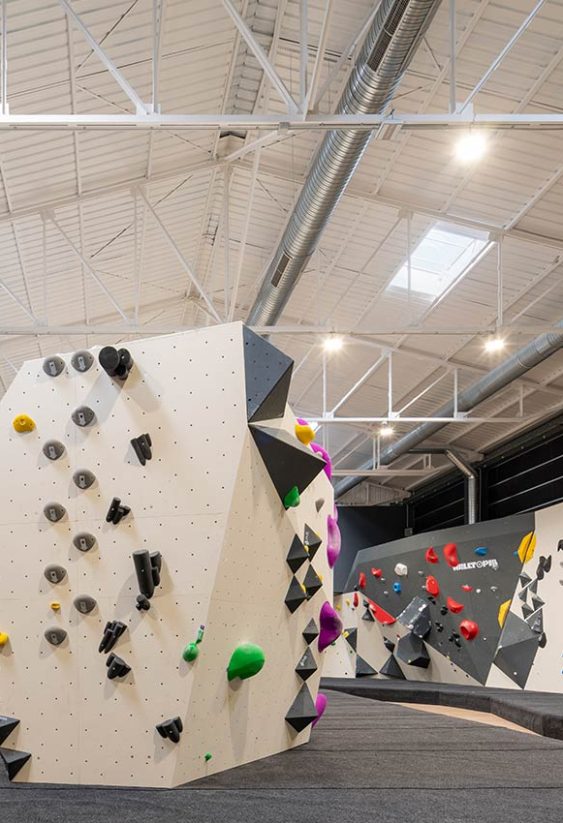 Rocódromo interior con bloques de escalada independientes y paredes con presas de colores bajo techo industrial.