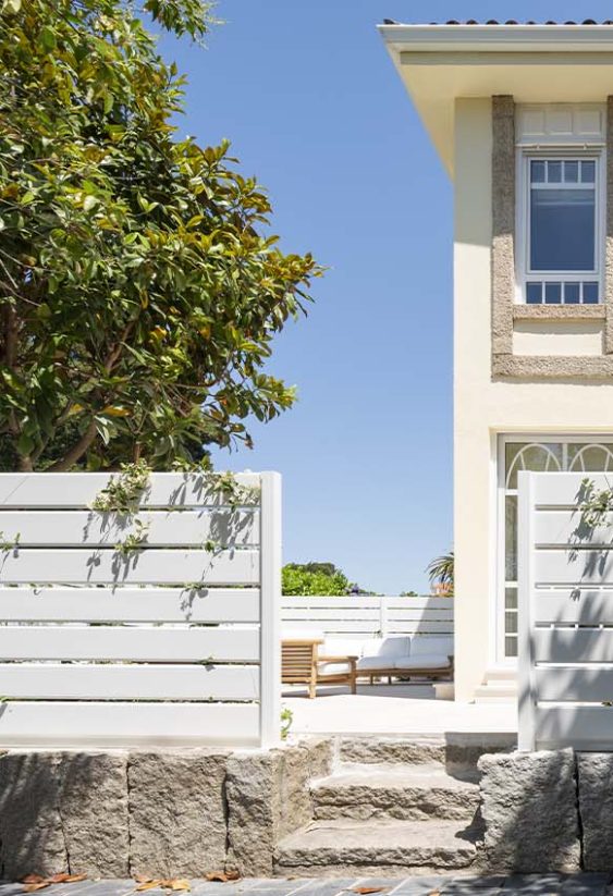 Fachada de vivienda unifamiliar con diseño sobrio, ventanales que conectan interior y exterior y una pequeña entrada con tres escalones.